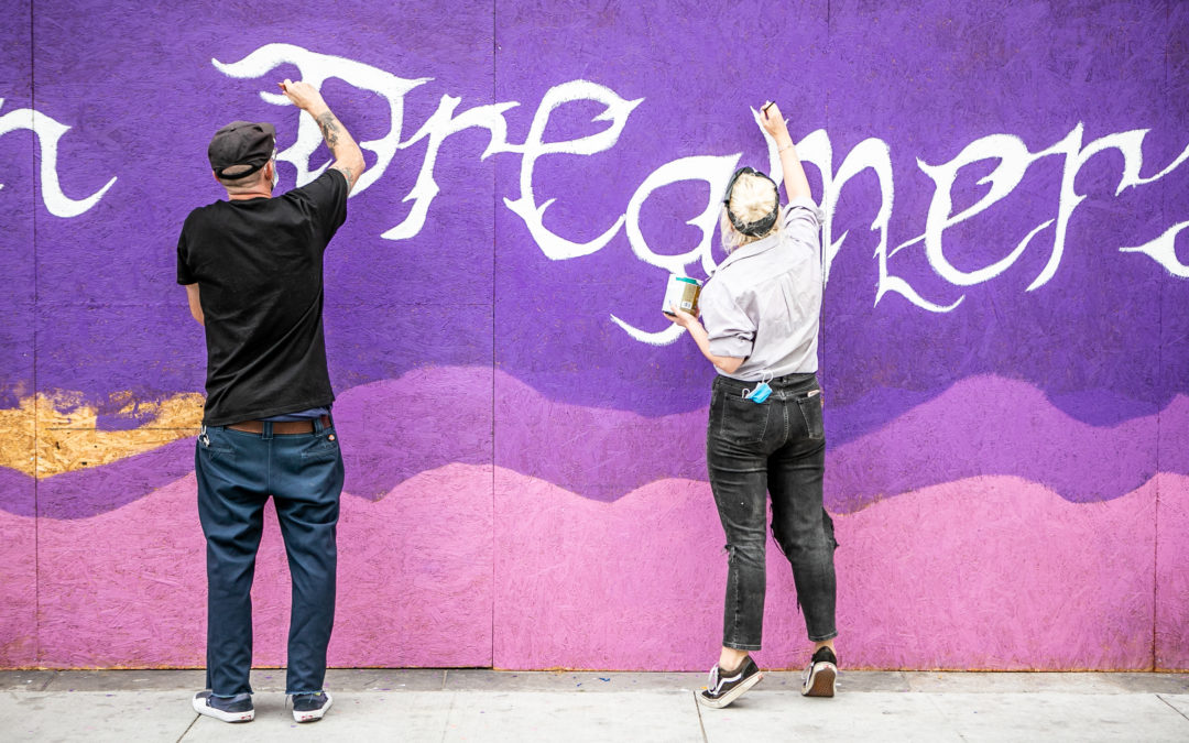 Two artists paint mural that says "dreamers"